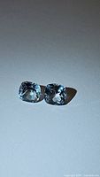 Pair of small cushion cut natural sky blue topaz gemstones showing color and cut.