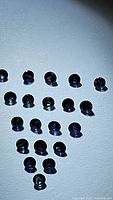 Top view of 20 small round sapphire gemstones in shades of cornflower and royal blue, arranged in rows on a light background.