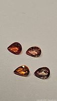 Four pear cut sapphires on neutral light background showing natural colors and cut from various angles