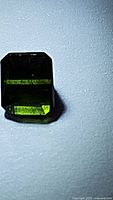 Close-up photo of octagon cut green tourmaline gemstone showing color and faceting under light.