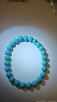 Full view of turquoise bracelet laid flat showing round polished robin's egg blue beads with natural matrix.