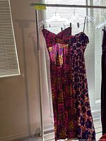 Two vintage maxi dresses hanging on hangers, showing full length and patterns