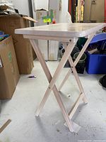 Side view of single folding table showing wooden legs in X-style folding position with light wood tone rectangular top.