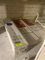 Three boxed Christmas trees in a basement or crawl space environment.