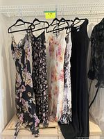 Five dresses hung side by side on hangers