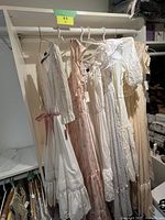 Six dresses hanging on a closet rod showing entire lot