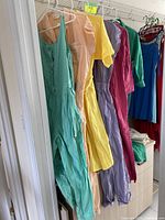Six pastel jumpsuits hanging on wire rack