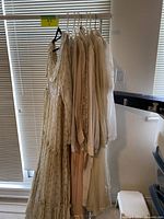 Overview of eight prairie-style dresses hanging on a rack showing colors and styles