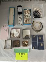 Overview of the lot showing multiple boxes of assorted costume jewelry, loose pearl strands, and a large silver-tone necklace.