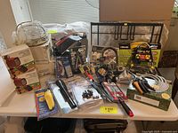 Lot of assorted household hand and yard tools including boxed items, lights, clamps, and various tools arranged on table