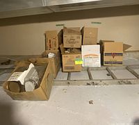 Multiple cardboard boxes on shelving containing loose clear jars and lids