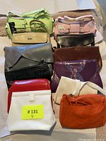 Photo showing front view of 10 assorted purses arranged upright on a table, showcasing various colors and styles.