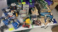 Lot of various painting supplies, flashlight boxes, and handheld spotlight on a table