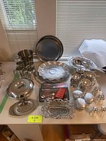 Overview of the 29-piece set showing various silver and stainless steel dining and serving pieces arranged on a table.