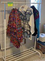 Four vintage fleece clothing items hanging on a rack inside a room, two jackets and two pairs of pants visible.