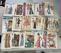 Fourteen pattern envelopes laid out on table, brands Simplicity, Butterick, McCall’s