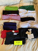 Top view of folded assorted tube tops and short sleeve tops in multiple colors including black, green, white, striped, purple and red