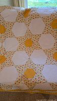 Quilt spread showing hexagonal white patches, yellow hexagons, and yellow floral print connecting pieces.