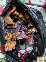 Bag containing wooden reindeer ornaments, plush animal ornaments, and a variety of other Christmas decorations including sparkly snowflakes and plastic balls.