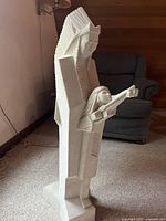 Front view of full sculpture showing angular form and figure with arms extended holding bow and arrow.