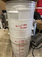 Stack of four white plastic storage containers showing 22 quart and liter measurement markings and side handles.