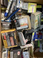 Drawer containing assorted boxes of screws, nails, and fasteners packed together