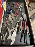 Photo of drawer with various pliers, locking pliers, wire cutters, and channel lock wrenches in used condition.
