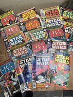 Photo showing 18 Star Wars comic books with various colorful covers featuring main characters and scenes from the Star Wars franchise. Comics show wear consistent with used condition but appear in good overall shape.