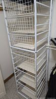 Full view of tall white metal wire shelving unit with seven drawers visible.