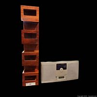 Photo showing the Brookstone CD player and AM/FM stereo unit next to the tall wooden display shelf with four open compartments.