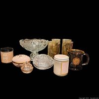 Full lot on black background showing all items: two candles, glass dessert bowl, crystal egg jewelry box, porcelain egg jewelry box, four amber drinking glasses, small bunny glass container, Ronald Reagan signed mug