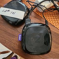 Two black Roku TV streaming devices with visible cables and Roku purple tabs on the side.