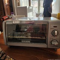 Black & Decker toaster oven with glass door and control dials on a table.