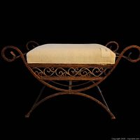 Vanity chair or stool front view showing entire iron frame with scrollwork and beige upholstered cushion.