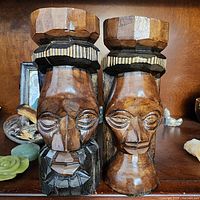 Pair of hand carved male and female wooden totems approximately 6 inches tall with detailed facial features, geometric carvings and painted accents.