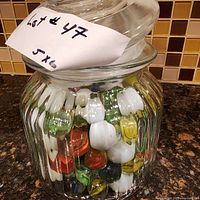 Front view of jar showing colorful marbles inside, jar lid angled on top