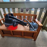Wide shot of small red and black shop vac and small grey steam cleaner on wooden bench.