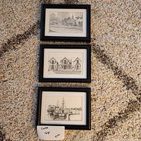 Three black framed wall art pieces laid out on carpet, showing all three signed sketches together.