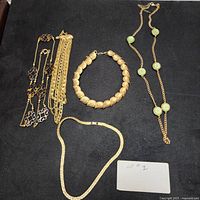 Lot of 5 gold tone vintage necklaces displayed on black background