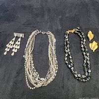 Overall view of the jewelry set including four pieces on a black surface.