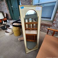 Full view of the vintage solid wood wall mirror showing the cream-colored frame with decorative detail and clear reflective glass, positioned standing outdoors.