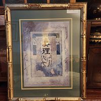 Framed wall art piece showing Asian calligraphy with textured blue and purple background within a gold-toned bamboo style frame.