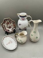 Five vintage ceramic and porcelain items arranged together showing details of Belleek Shamrock cream jug, Shamrock pitcher, Coalport Caughley jug, Masons Mandalay Blue nut dish, and small white Lisbon dish.