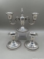 Front view showing two-arm candelabra and pair of single candlesticks arranged together