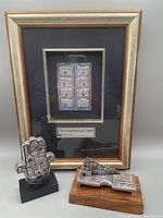 Framed plaque with eight sterling gates, black mat, and gold-toned frame alongside two silver Jerusalem sculptures on black and wooden bases.