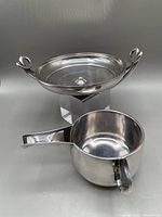 Two silver plate items consisting of a Greek kylix reproduction and a Roman trulla reproduction with handles, shown together.