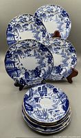 Four Blue Mikado pattern plates and saucers displayed on stands and stacked, showing various sizes and designs.