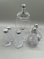 Photo showing all crystal salt and pepper shaker sets and the silver overlay perfume bottle on display.