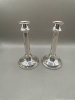 Front view of both sterling silver candlesticks showing round bases and tapered stems