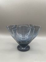 Front view of a blue translucent glass vase with a handkerchief shape on a solid base.